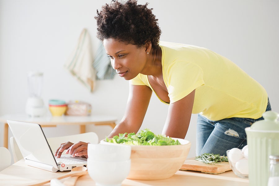 Placeholder Image Fit woman looking at computer and cooking