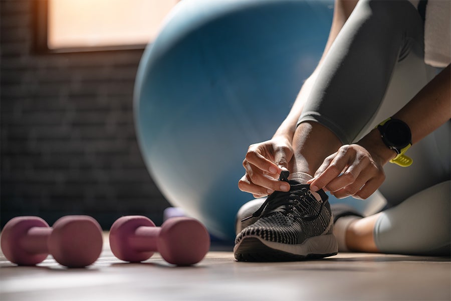 Training Woman lacing up sneakers in gym
