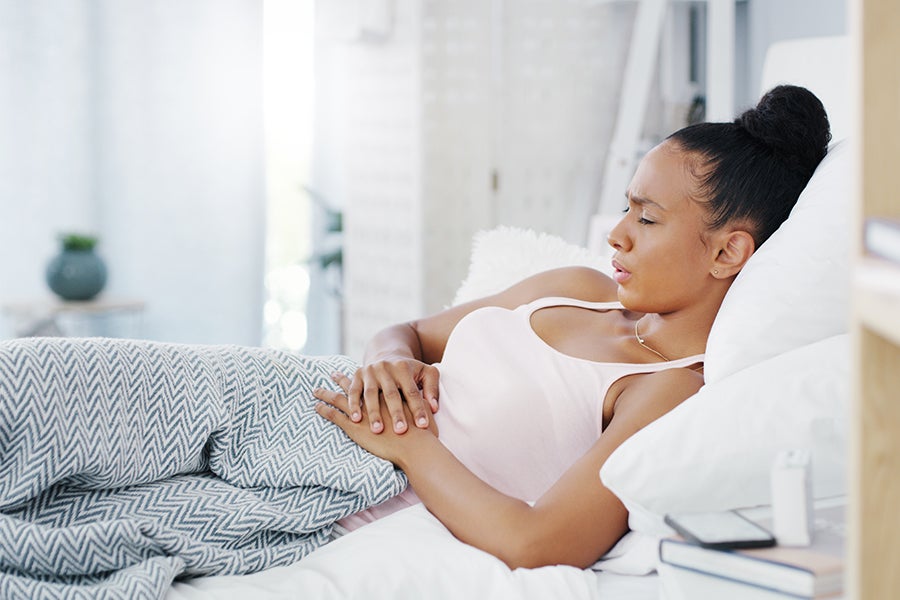 PMS Article Woman with cramps laying in bed