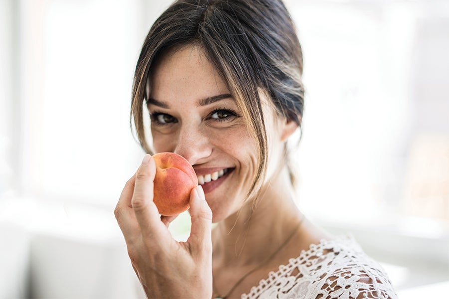In Your 40s Woman smiling holding up healthy fruit