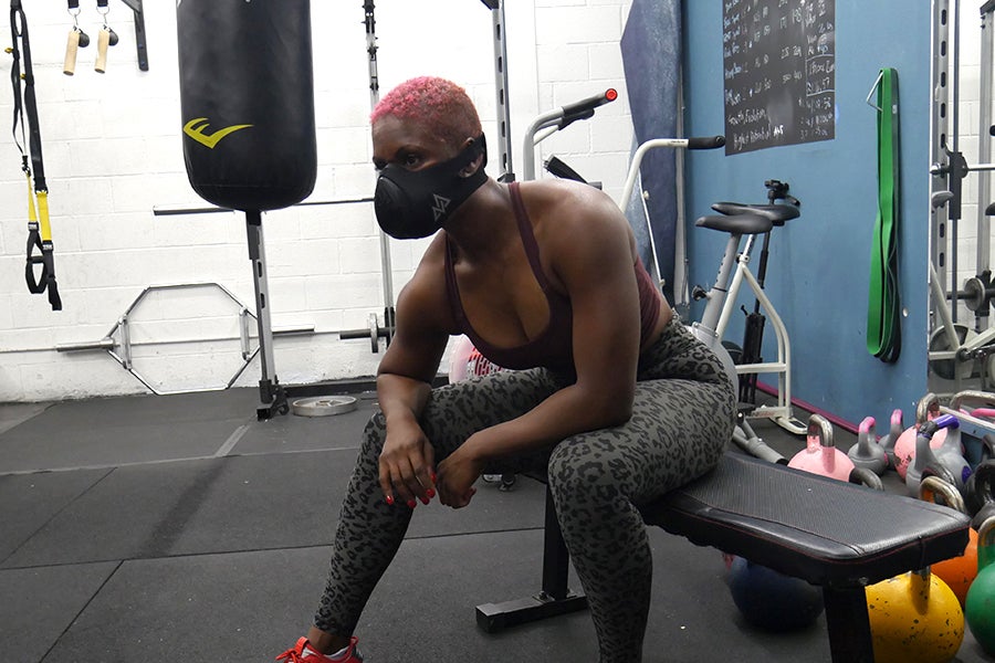 TrainingMaskDanielle1 Woman sitting on exercise bench in gym with face mask on
