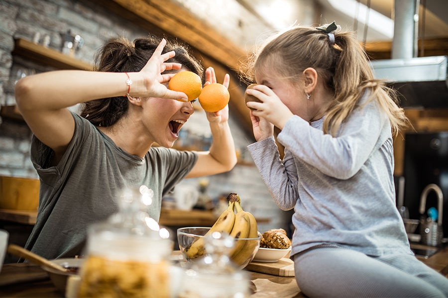 Mother and daughter playing with fruit in the kitchen to discourage picky eating
