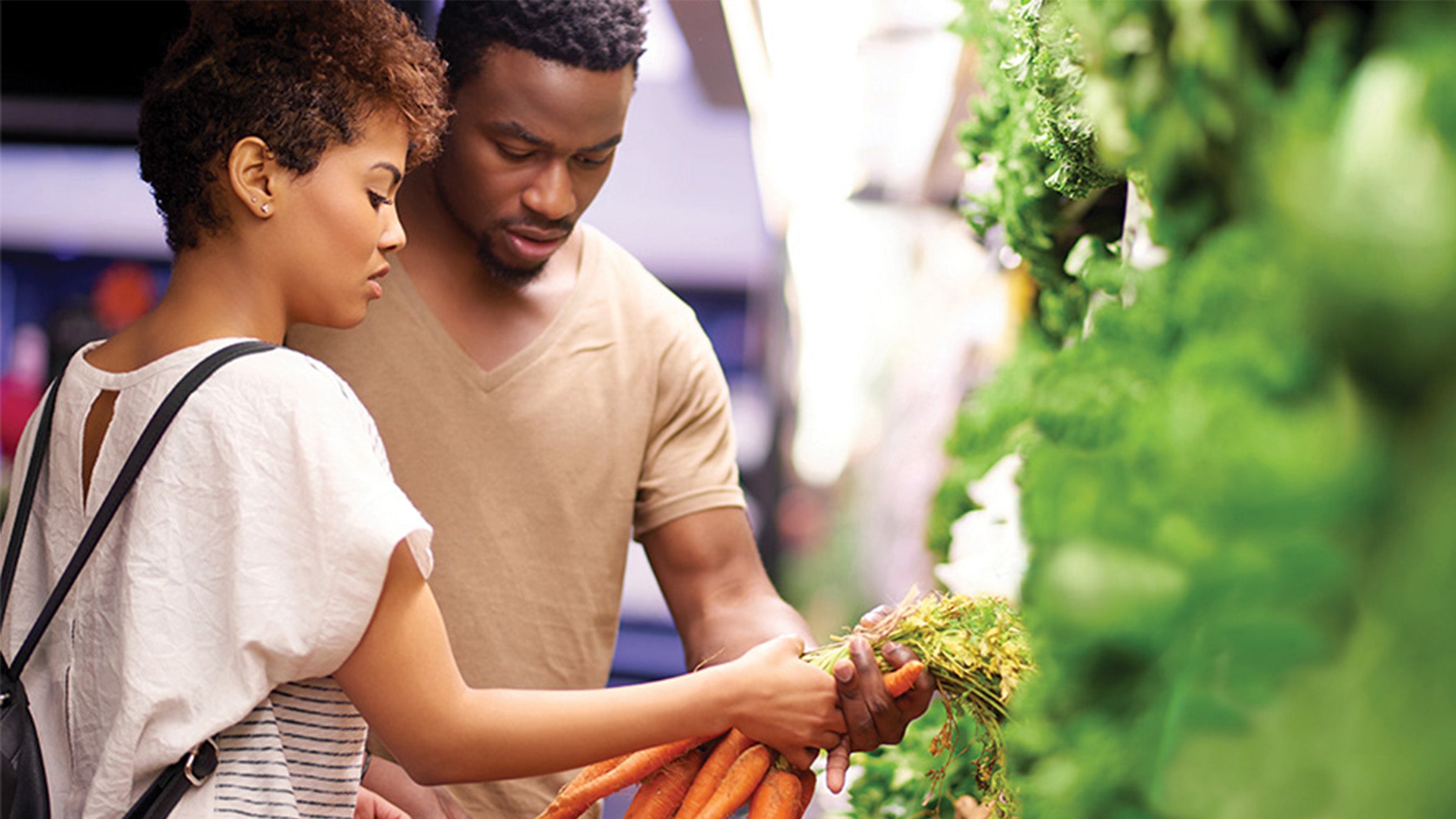 Couple at the grocery store picking out produce.