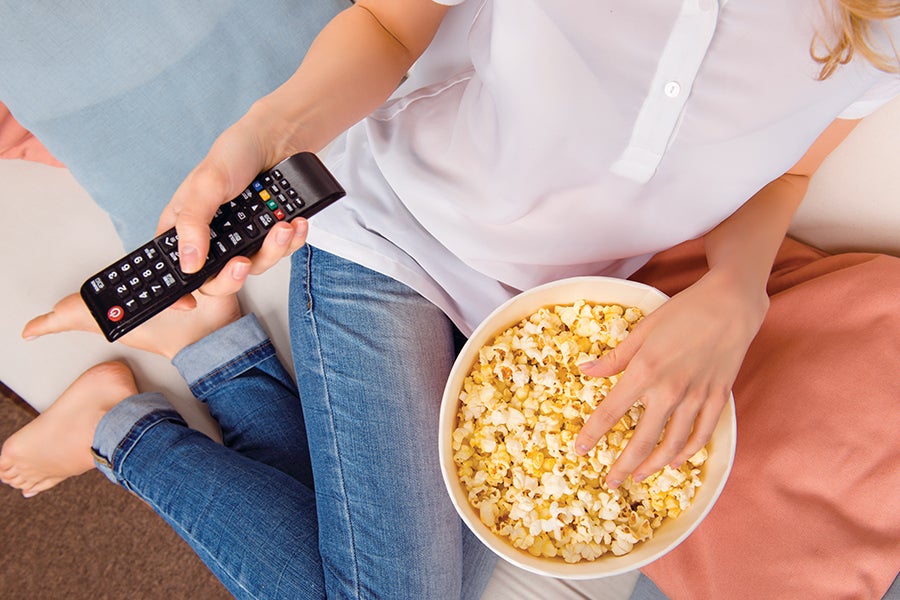 Woman watching TV with popcorn - habits that age