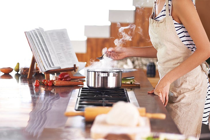 Promo Fit woman following recipe and cooking in kitchen