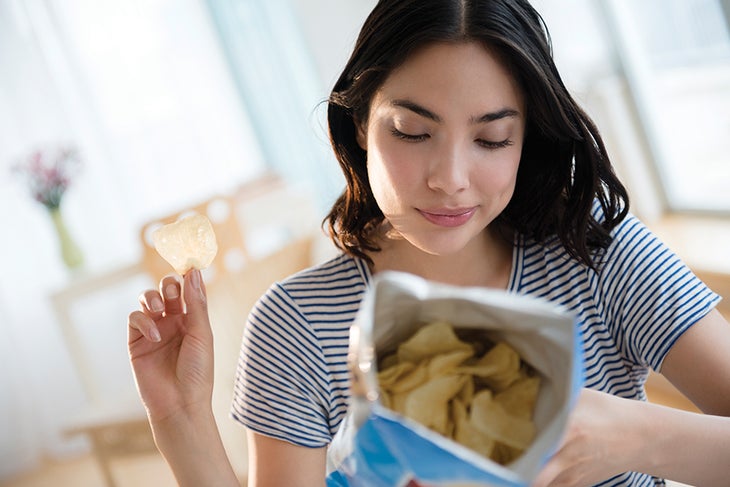 Ask the Nutritionist Woman looking at a bag of potato chip's nutrition label