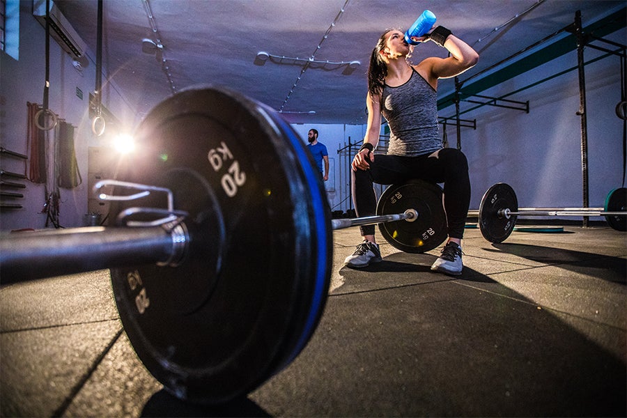Woman drinking preworkout before lifting at the gym