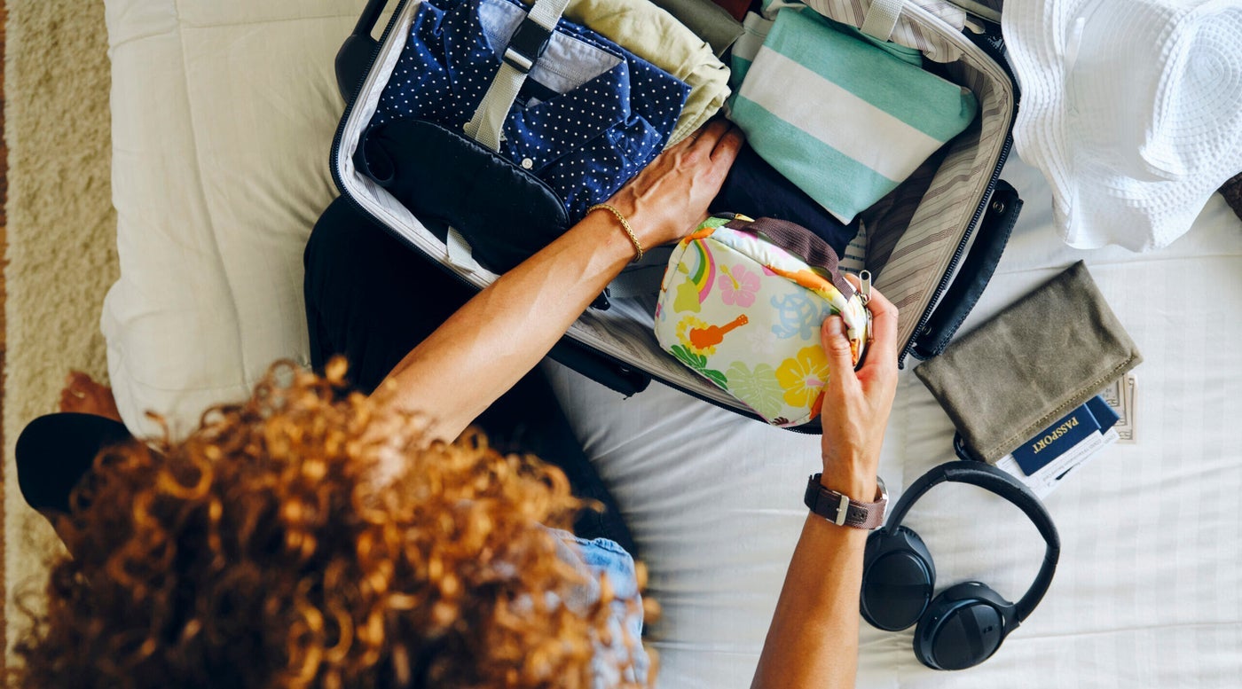 Woman Packing Suitcase With Wellness Travel Essentials