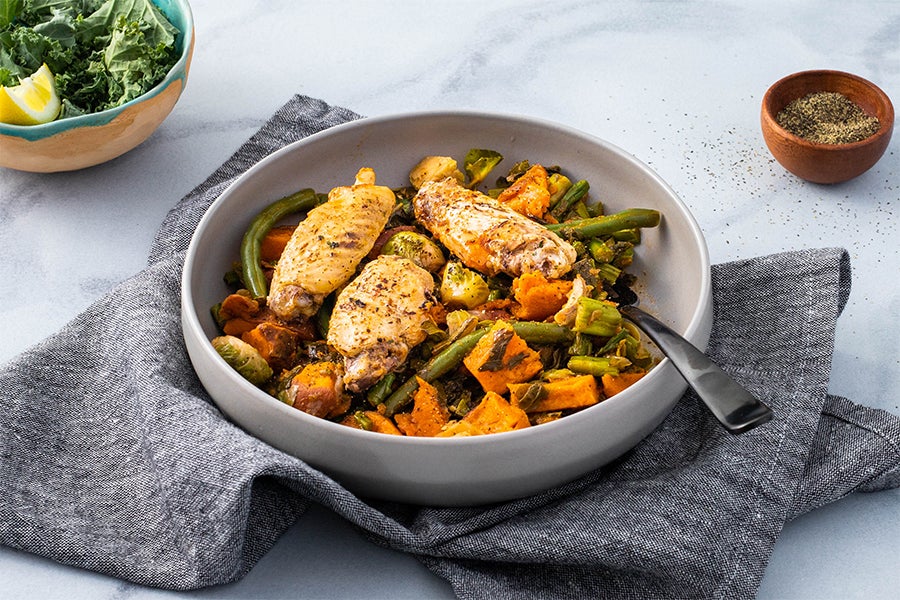 Chicken and veggies in a dish with napkin and garnish